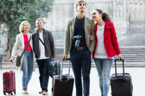 positive american family of four with trunks walking through city street